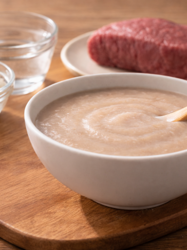 Korean Beef Rice Porridge (Sogogi-Mium) for 6-month-old baby served in a white bowl with smooth, silky texture and lean beef top round in the background