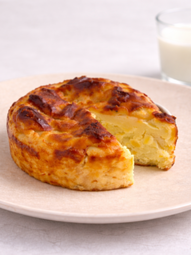 Baby sweet potato Basque cheesecake on a plate with a glass of milk in the background