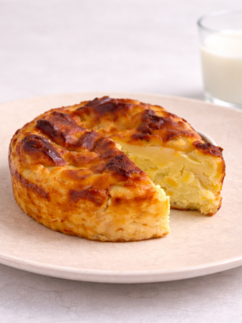 Baby sweet potato Basque cheesecake on a plate with a glass of milk in the background