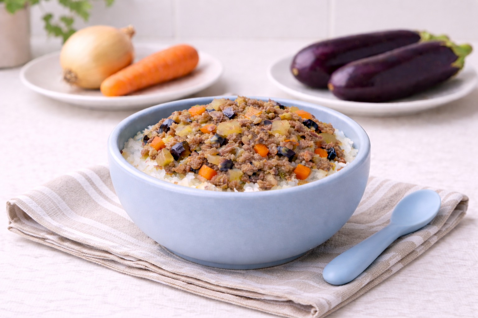 Beef eggplant rice bowl for babies served in a light blue baby bowl with diced beef, eggplant, carrot, and onion