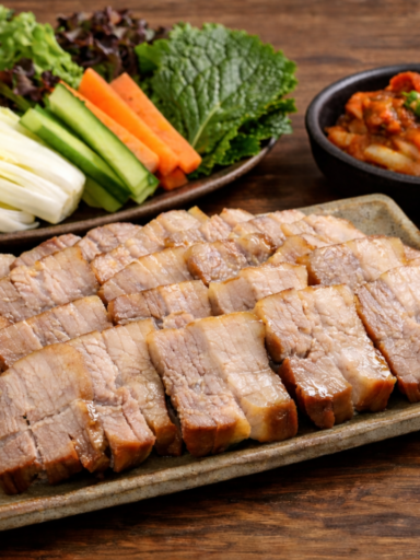 Korean bossam recipe with sliced boiled pork served with napa cabbage, kimchi and ssamjang