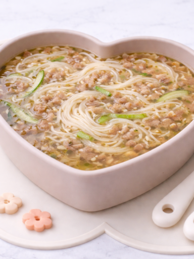 Korean baby noodle soup with beef and zucchini served in a heart-shaped plate for toddlers