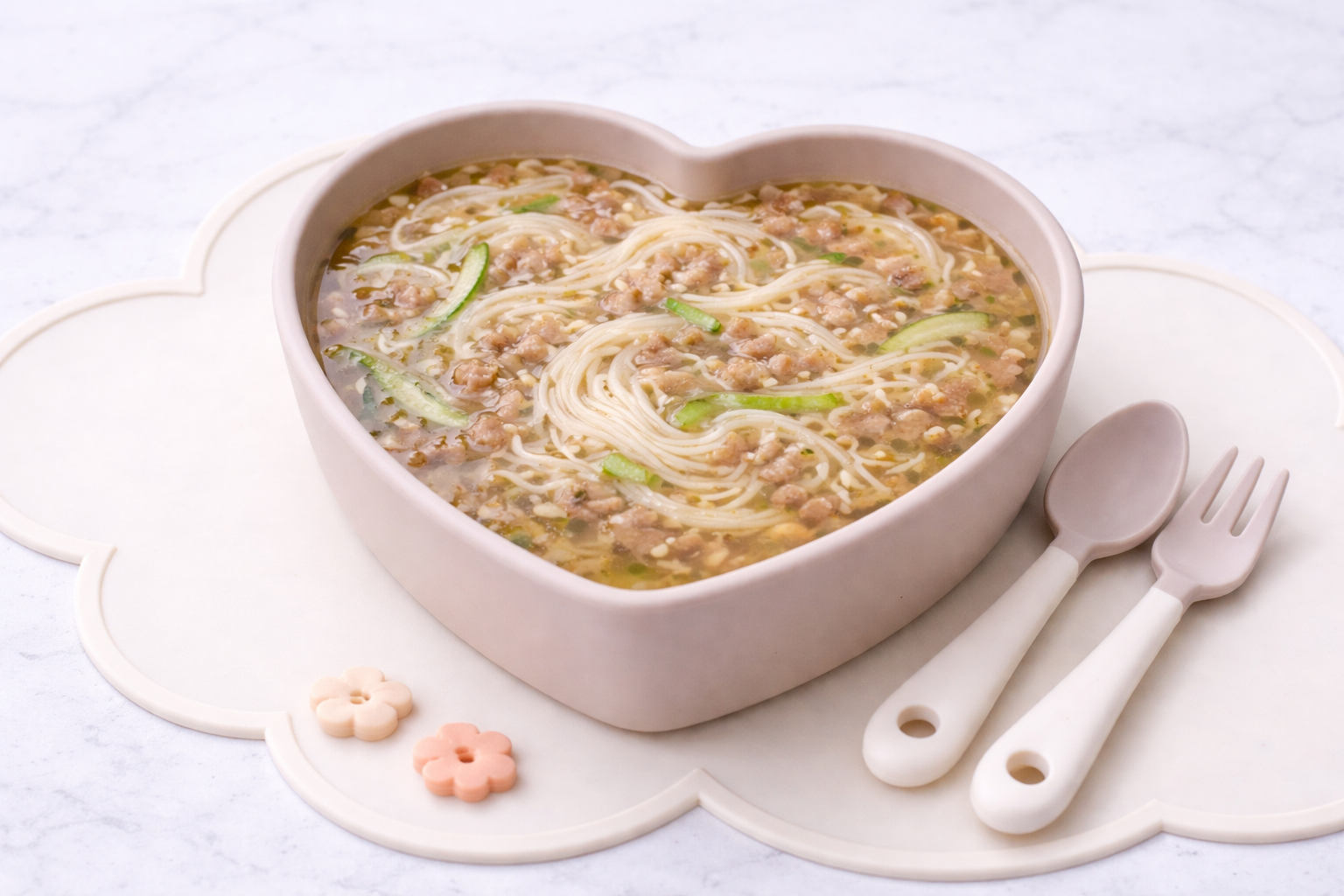 Korean baby noodle soup with beef and zucchini served in a heart-shaped plate for toddlers