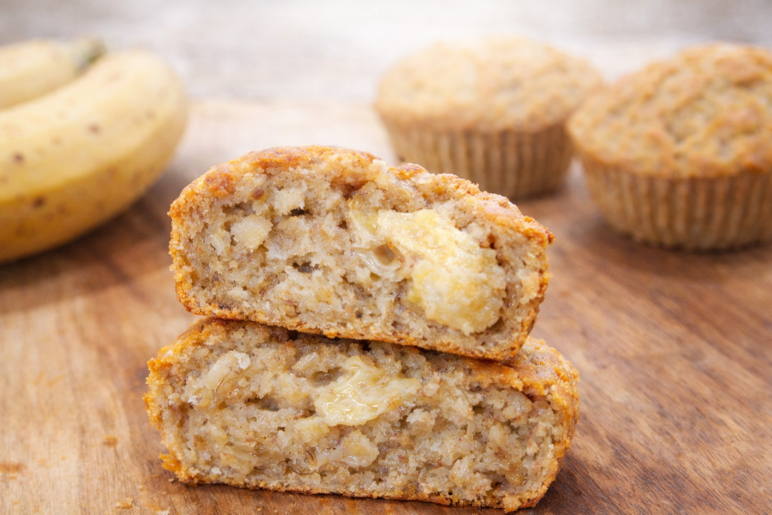 Soft and moist baby banana bread cut in half on a wooden board, showing fluffy texture and banana chunks